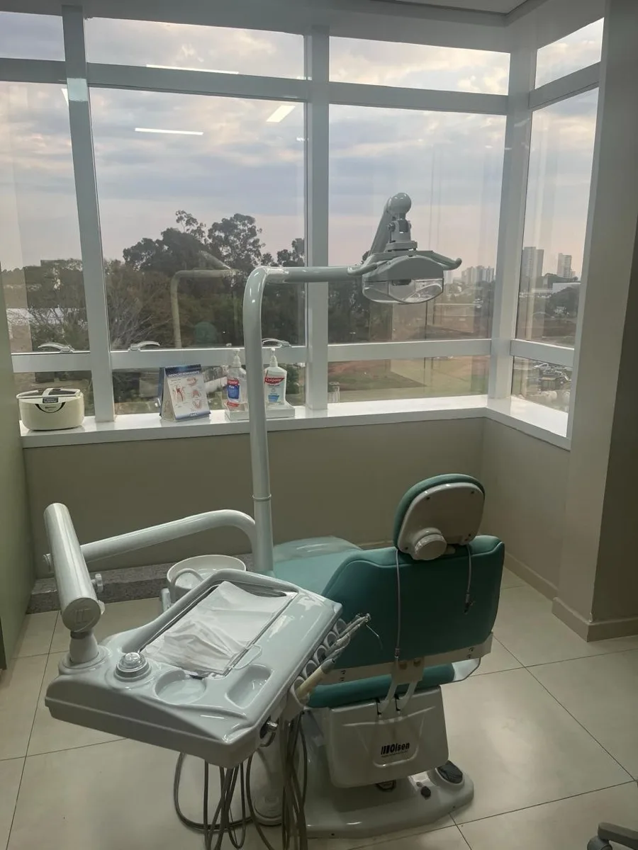 Sala de atendimento do consultório, com a cadeira odontológica junto à janela